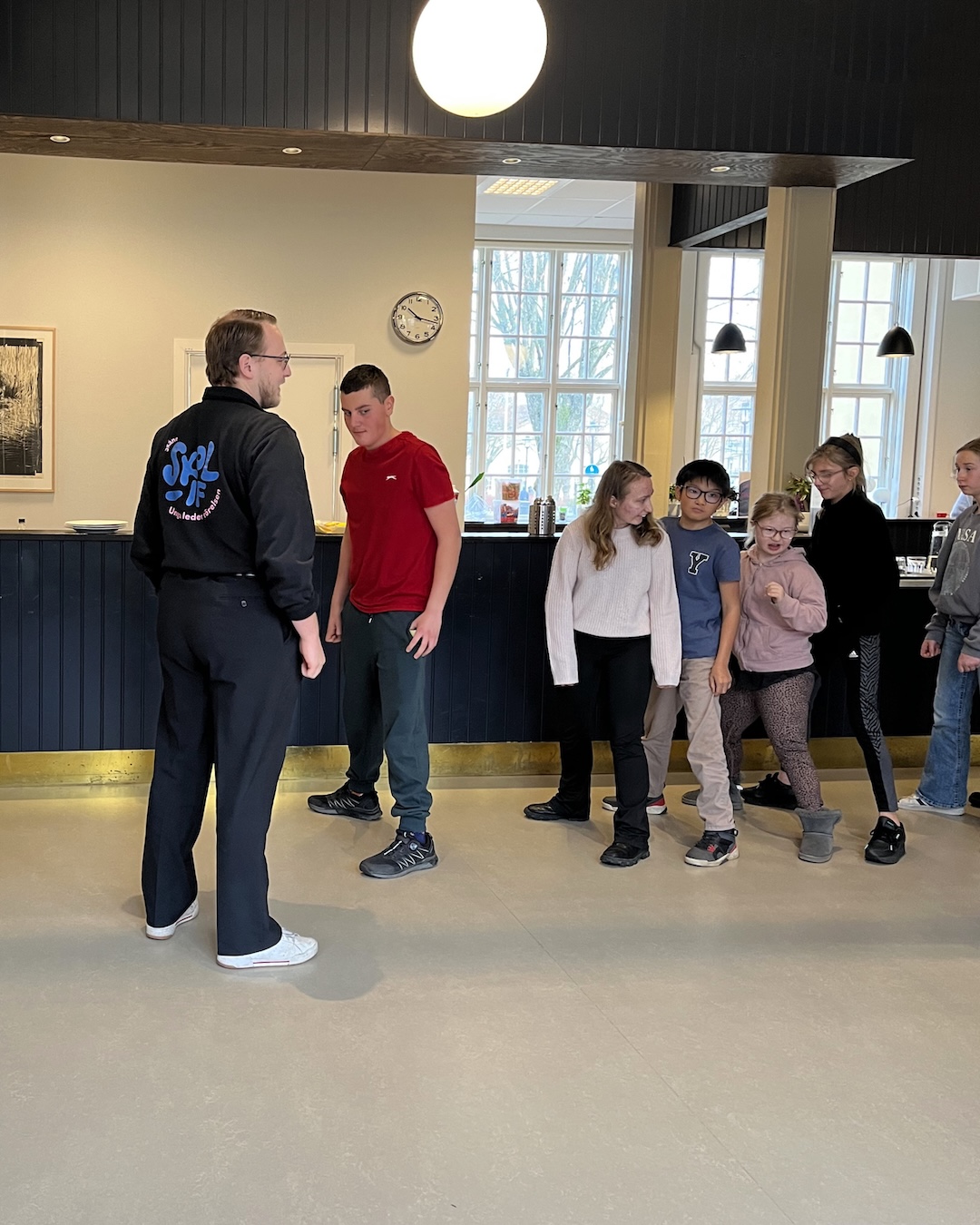 Unga ledare står på led och instrueras i en rörelseövning.