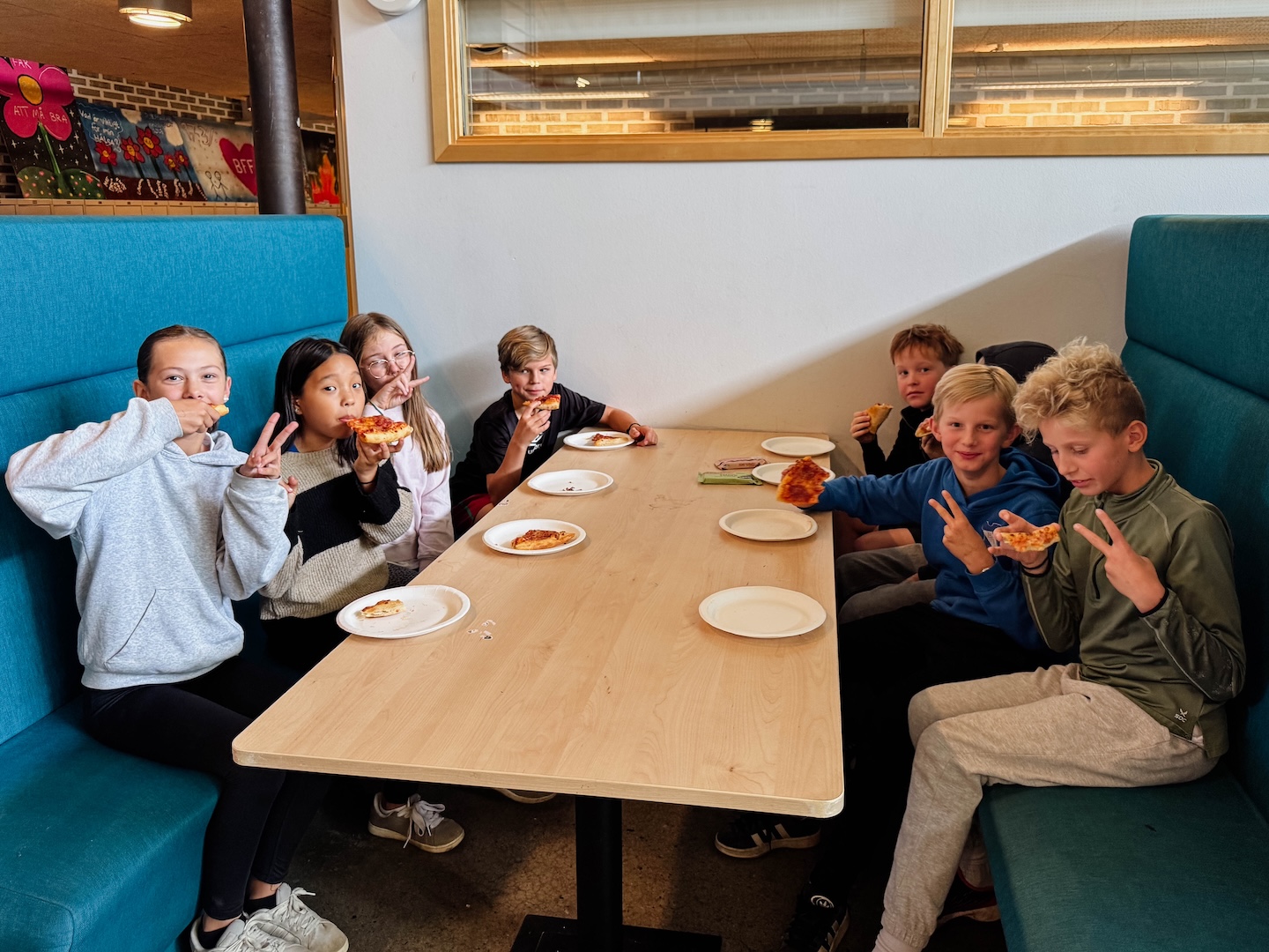 En grupp unga ledare som poserar glatt med pizza i handen. 