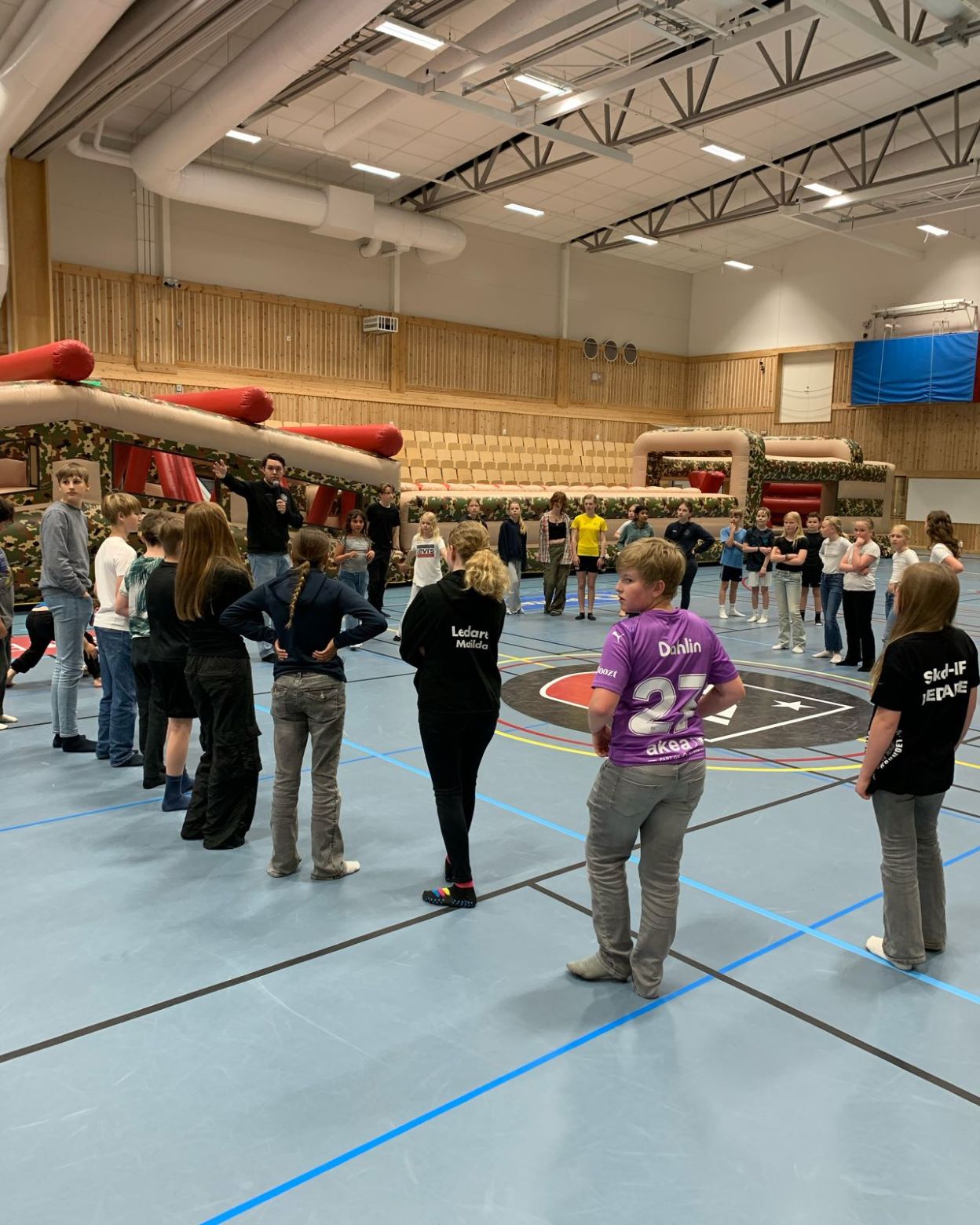 Unga deltagare står i en cirkel runt utbildningsansvarig Jacob Ericsson som berättar m aktiviteterna.